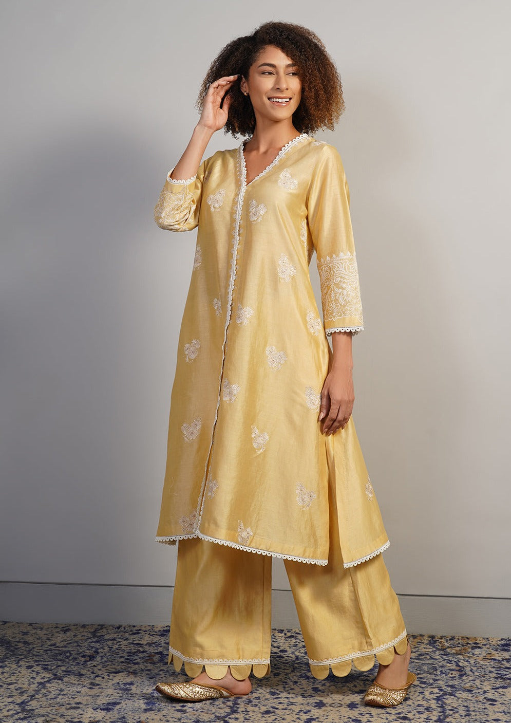 A pleasant, V-neck beige cotton silk suit set that is adorned with subtle aari work embroidery