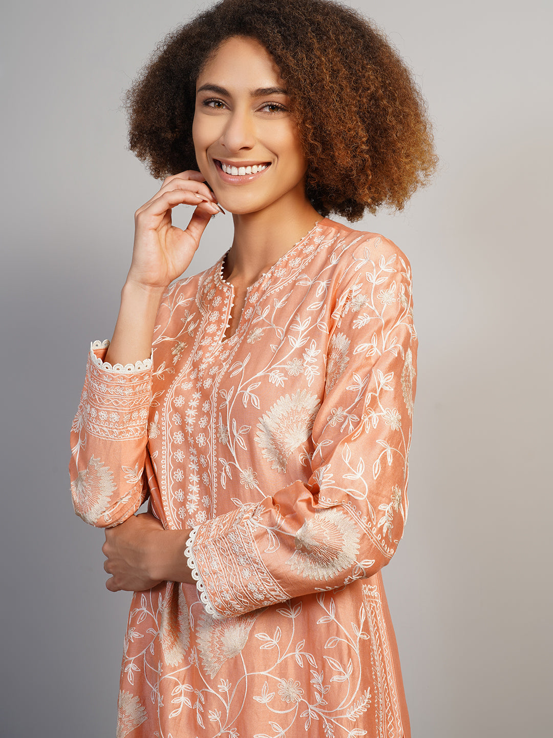 A gorgeous cotton silk suit set in peach that is adorned with Aari work in off-white silk yarn